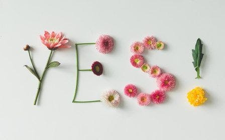 Ordet "yes" eller ja - laget av blomster på en lys bakgrunn 